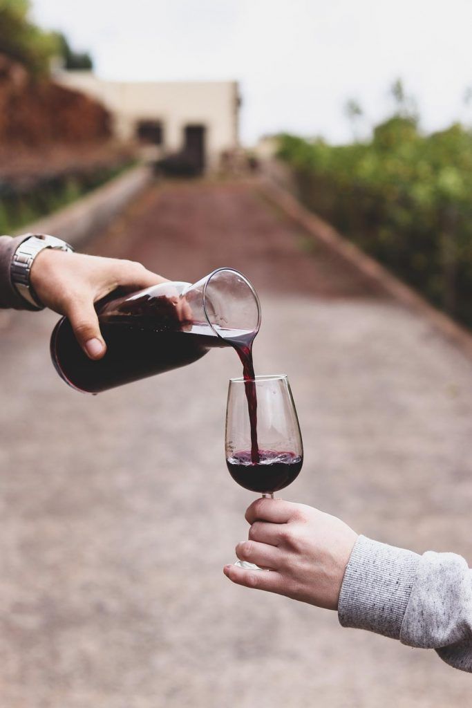 a glass of red win being poured outside bodega